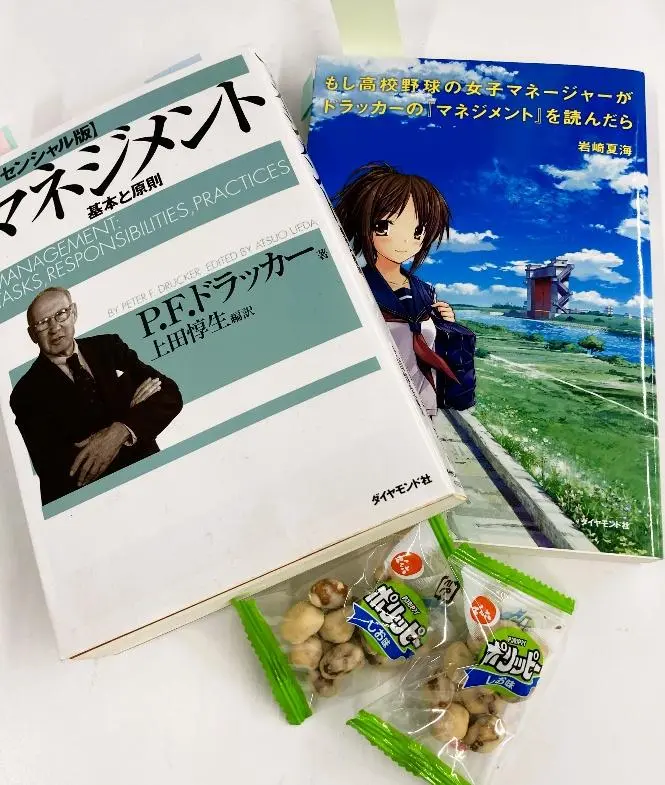 「マネジメント」と「もしも高校野球の女子マネージャーがドラッカーのマネジメントを読んだら」と豆菓子がおかれた机上